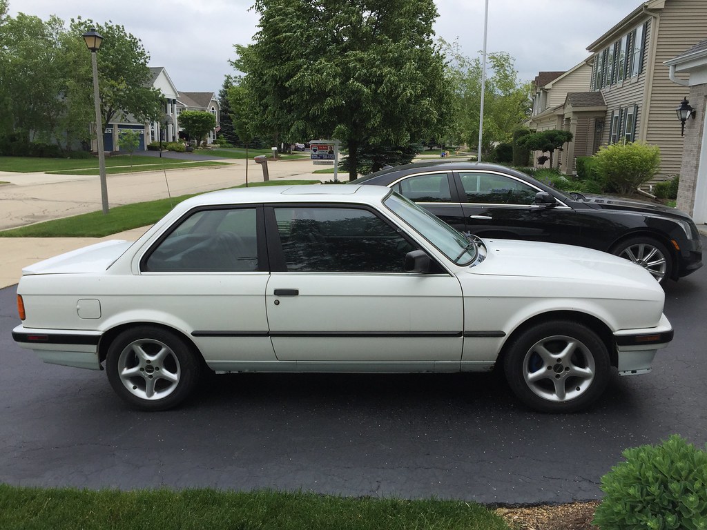 Before: white BMW E30 325is parked in a driveway before restoration